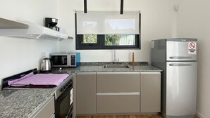 A compact kitchen with a microwave, toaster, kettle, and a stainless steel refrigerator.
