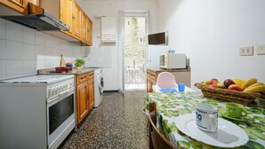 A compact kitchen with wooden cabinets, a stove, a washing machine, and a dining area with a table set for two.