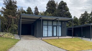 Un edifici modern amb entrada coberta, un camí de grava i una zona enjardinada.
