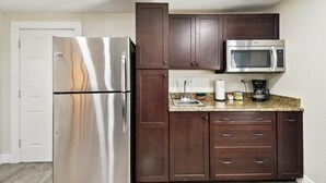 A kitchen with a stainless steel refrigerator, dark wooden cabinets, a granite countertop, a microwave, and a coffee maker. - Tampa Retreat – Perfect Location (Tampa)