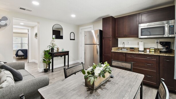 A modern kitchen with dark wooden cabinets, a stainless steel refrigerator, and a built-in microwave. - Tampa Retreat – Perfect Location (Tampa)