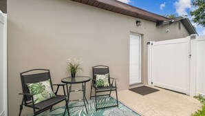 A patio with two chairs and a small table, a white gate, and a door. - Tampa Retreat – Perfect Location (Tampa)