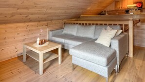 A cozy room with a grey sectional sofa, a small wooden table with a vase and candles, and wooden walls. - 2 bedroom lovely home in Erfjord (Erfjord)