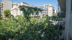 Un edificio residencial con balcones, cielo despejado y vegetación circundante.