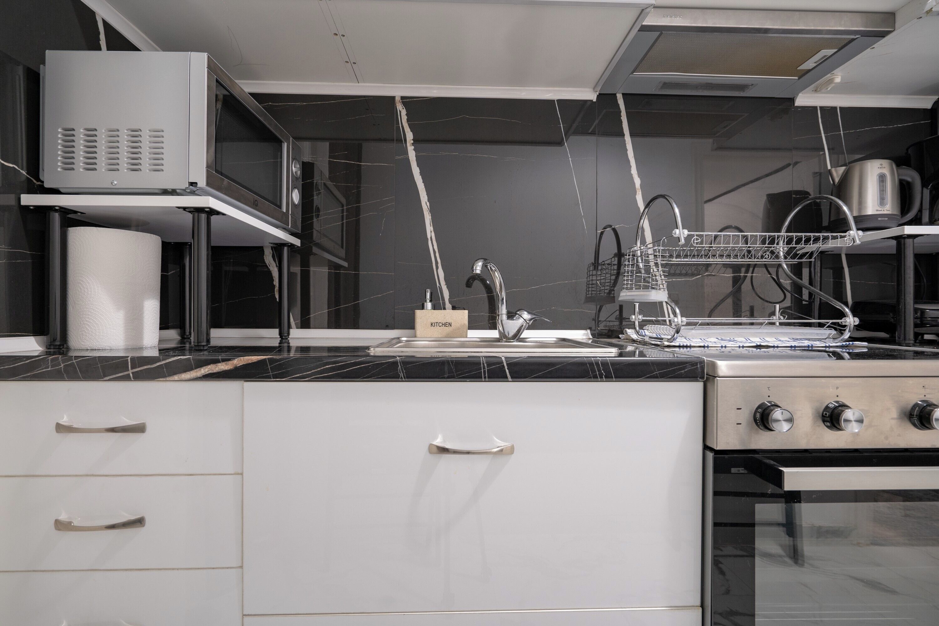 A kitchen with a stove, microwave, and dish rack.