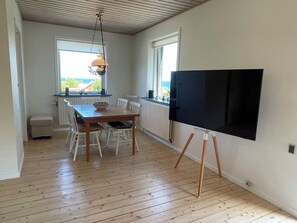 Une pièce comprenant une table à manger, des chaises, un tableau noir et une fenêtre donnant sur un paysage.