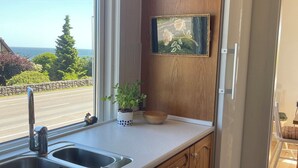 Una cocina con armarios de madera, un lavamanos doble, una pequeña planta en maceta y un cuadro en la pared.