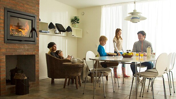 En matplats med en tegelbeklädd öppen spis, moderna stolar och ett matbord.