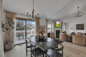A spacious living area with a dining table, chairs, a TV, and a fireplace.