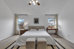 Un dormitorio con una cama grande, mesitas de noche, un escritorio y un ventilador de techo.