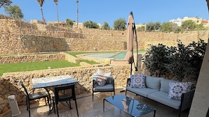 An outdoor patio area with stone walls, a pool, and a view of the surrounding landscape.