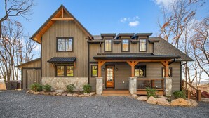 A two-story house with a stone foundation, wooden siding, and a prominent front porch.