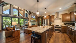 A spacious kitchen with a large island, wooden cabinets, and a stone fireplace.