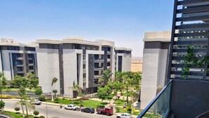 A modern apartment complex with multiple buildings, a roundabout, and a view from a balcony with outdoor furniture. - 3-bedroom apartment in cool Cairo with WiFi, AC (Cairo)