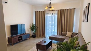 A living room with a flat-screen TV, a sofa, a coffee table, and a potted plant. - 3-bedroom apartment in cool Cairo with WiFi, AC (Cairo)
