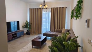 A living room with a flat-screen TV, a sofa, a coffee table, and a potted plant. - 3-bedroom apartment in cool Cairo with WiFi, AC (Cairo)
