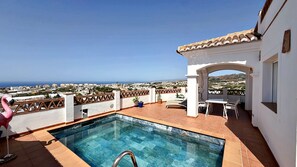 A rooftop pool with a view of the sea, a white building with a tiled roof, and a flamingo statue. - AP418 VILLA MARIVI (Torrox)