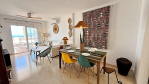 A dining area with a table set for four, a sofa, a patterned wall, and a view through a glass door. - AP418 VILLA MARIVI (Torrox)