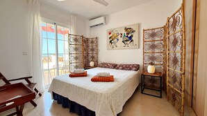 A bedroom with a bed, a chair, a table, and a balcony view. - AP418 VILLA MARIVI (Torrox)