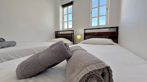 A hotel room with two beds, a window, and a nightstand with a lamp.