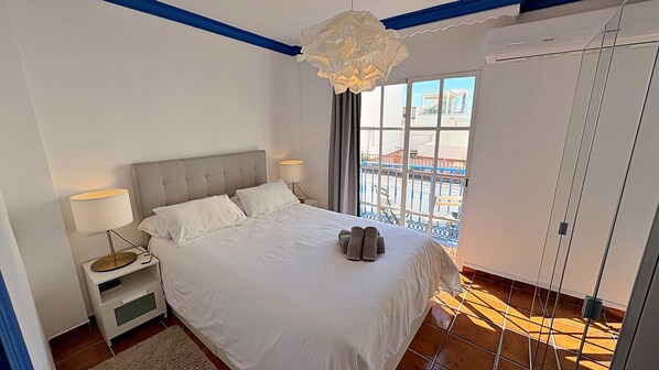 Un dormitorio con cama, lámparas de noche, una ventana con vistas y una lámpara en el techo.