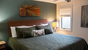 A bedroom with a bed, pillows, a headboard, a wall art piece, a window with blinds, and a bedside lamp. - Powderidge 15 Slope Side (Snowshoe)
