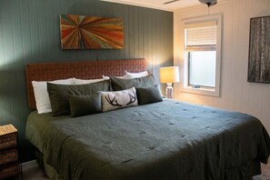 A bedroom with a bed, pillows, a headboard, a wall art piece, a window with blinds, and a bedside lamp. - Powderidge 15 Slope Side (Snowshoe)