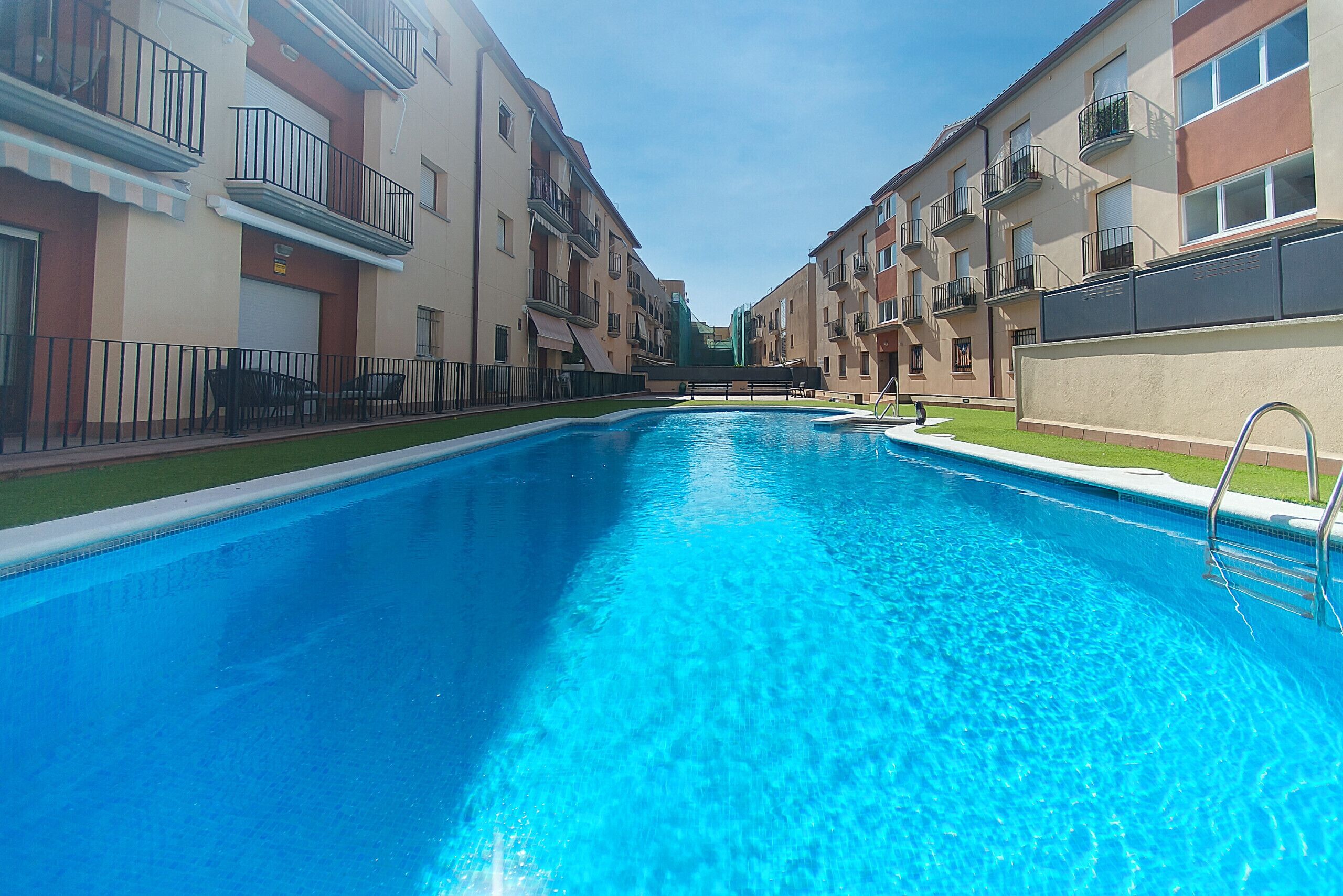 A swimming pool surrounded by apartment buildings with balconies.