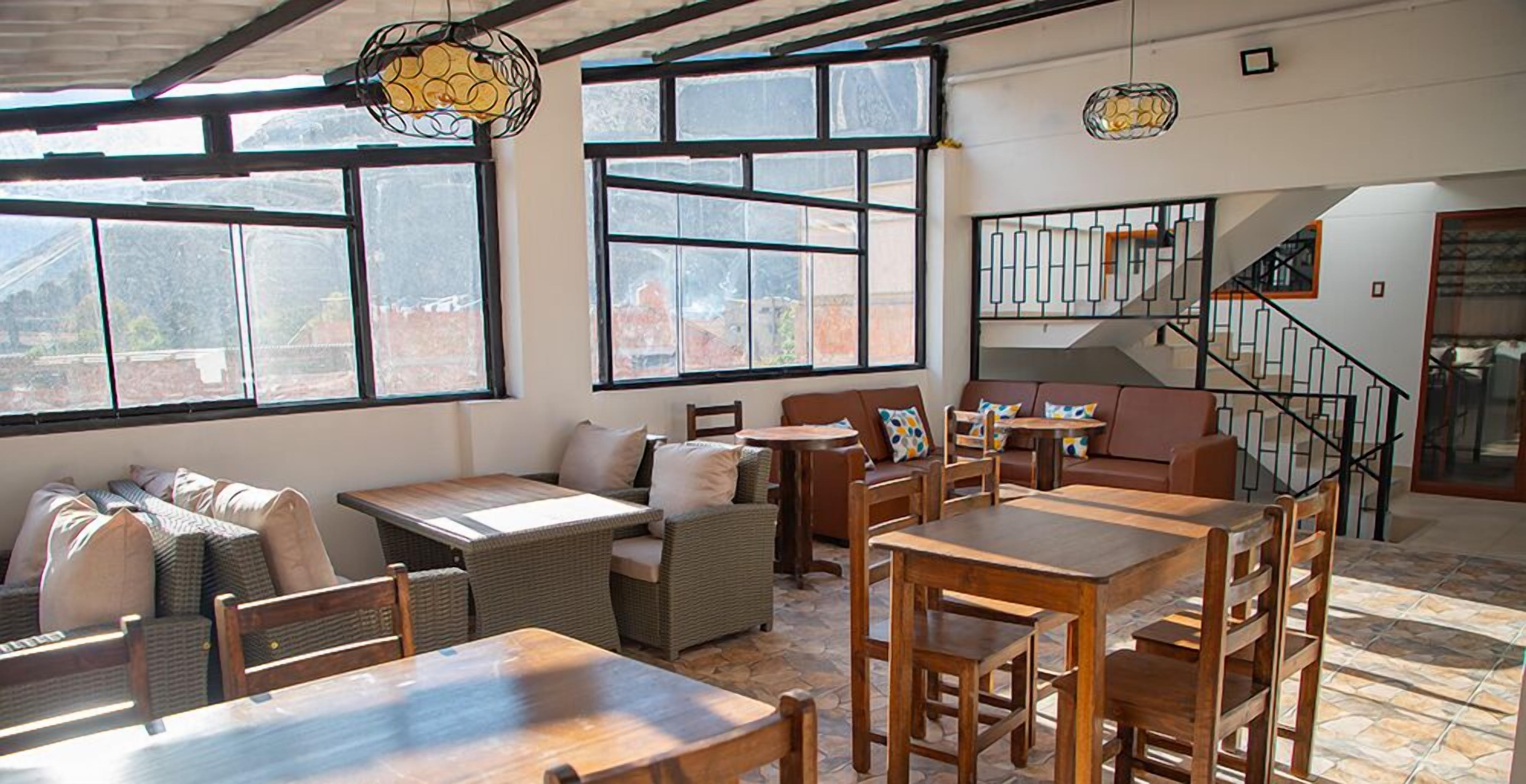 A spacious dining area with high ceilings, large windows, and a staircase leading to an upper level.