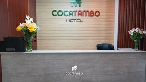 Un comptoir d’accueil à l’hôtel Cocatambo, avec un panneau en bois servant de décor et le logo de l’hôtel.