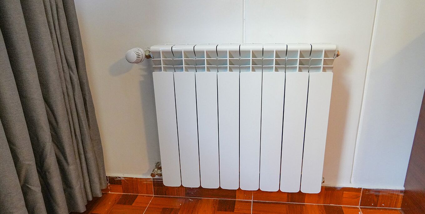 A white radiator with a vent and a control knob on the left side.