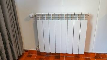 A white radiator with a vent and a control knob on the left side.