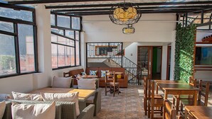 Un intérieur chaleureux avec un canapé, une table à manger et des chaises, un escalier et de grandes fenêtres.