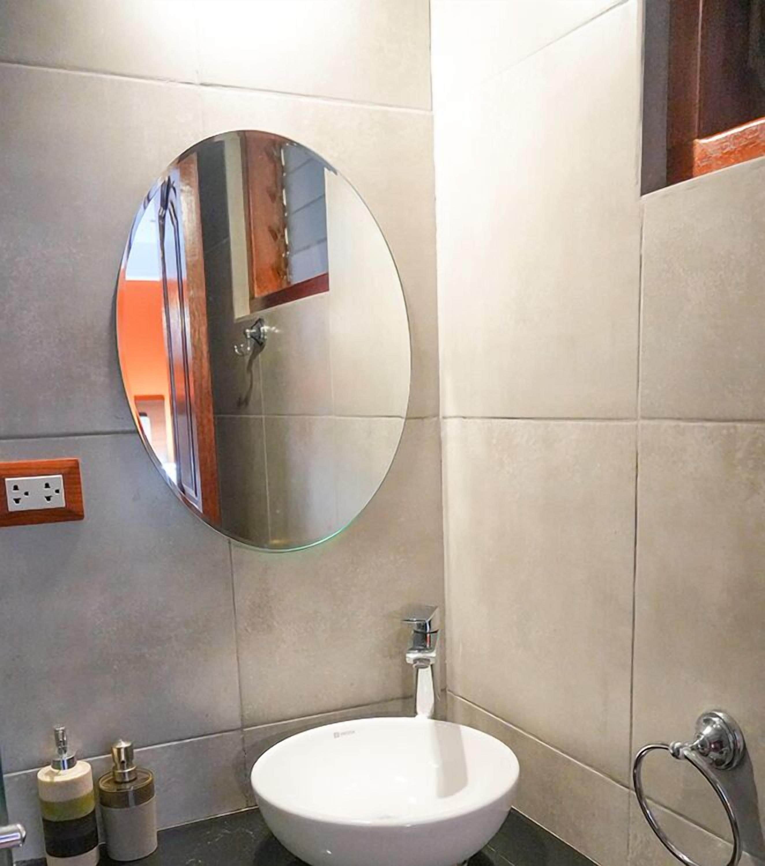 A bathroom with a round mirror, a white sink, and a towel rack.