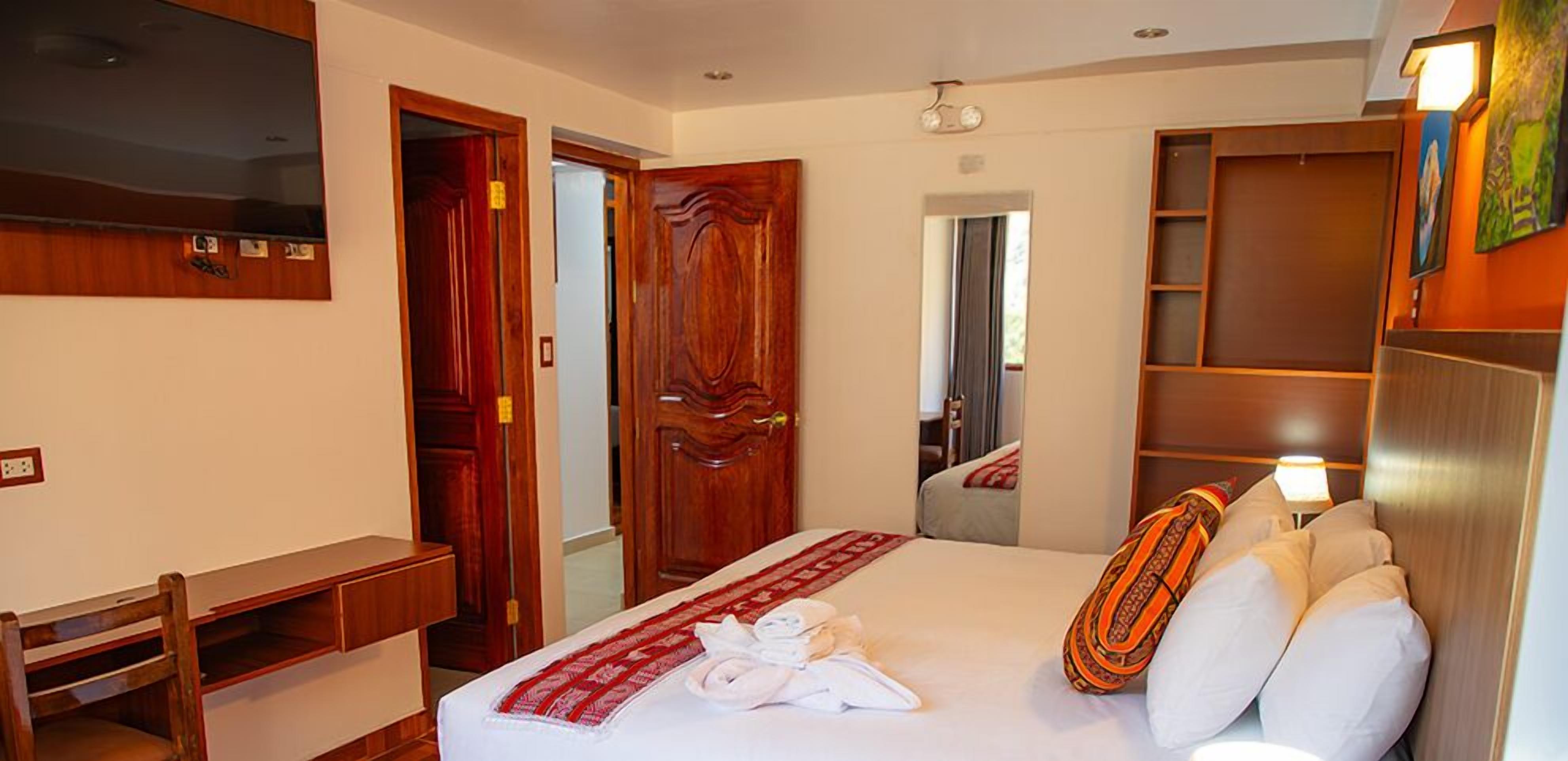 A hotel room with a bed, a desk, a mirror, and a wardrobe.