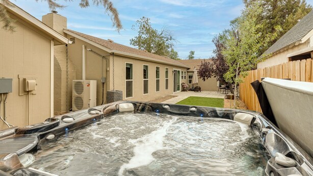 A backyard with a hot tub, a covered patio, and a wooden fence. - Midtown Reno 1br W/ share Hot Tub & Backyard (Reno)