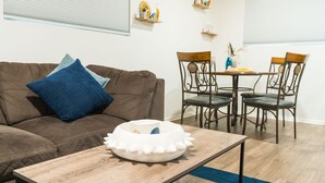 A living room with a brown sofa, a coffee table, and a dining table with chairs. - Midtown Reno 1br W/ share Hot Tub & Backyard (Reno)