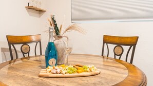A round wooden table with a bottle of blue liquid, a glass, and a wooden board with snacks. - Midtown Reno 1br W/ share Hot Tub & Backyard (Reno)