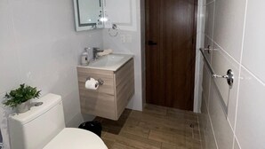 A small bathroom with a toilet, sink, and mirror.