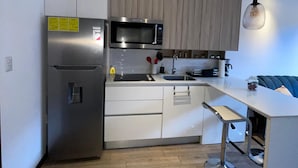 A modern kitchen with a built-in microwave, stainless steel refrigerator, and a wooden cabinet.