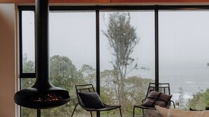 Un intérieur moderne avec une grande fenêtre, une cheminée et deux fauteuils.