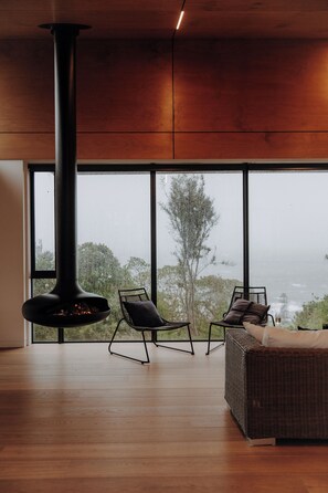 Un intérieur moderne avec une grande fenêtre, une cheminée et deux fauteuils.