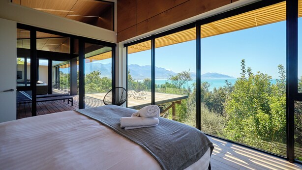 Une chambre avec un grand lit, une vue sur l’extérieur et un plafond en bois.
