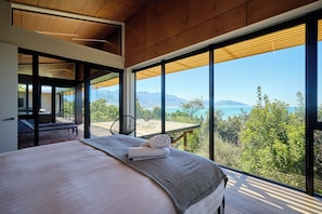 Una camera da letto con un letto grande, vista sull'esterno e soffitto in legno.
