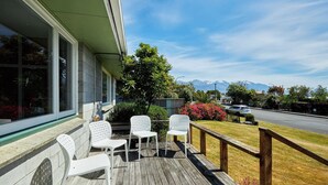 A wooden deck with white chairs and a view of mountains. - Close To Beach | Sunny | Getaway - KK16786 (Kaikoura)