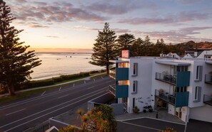 Un hotel moderno con vista sul mare, dotato di parcheggio e un edificio con balconi.