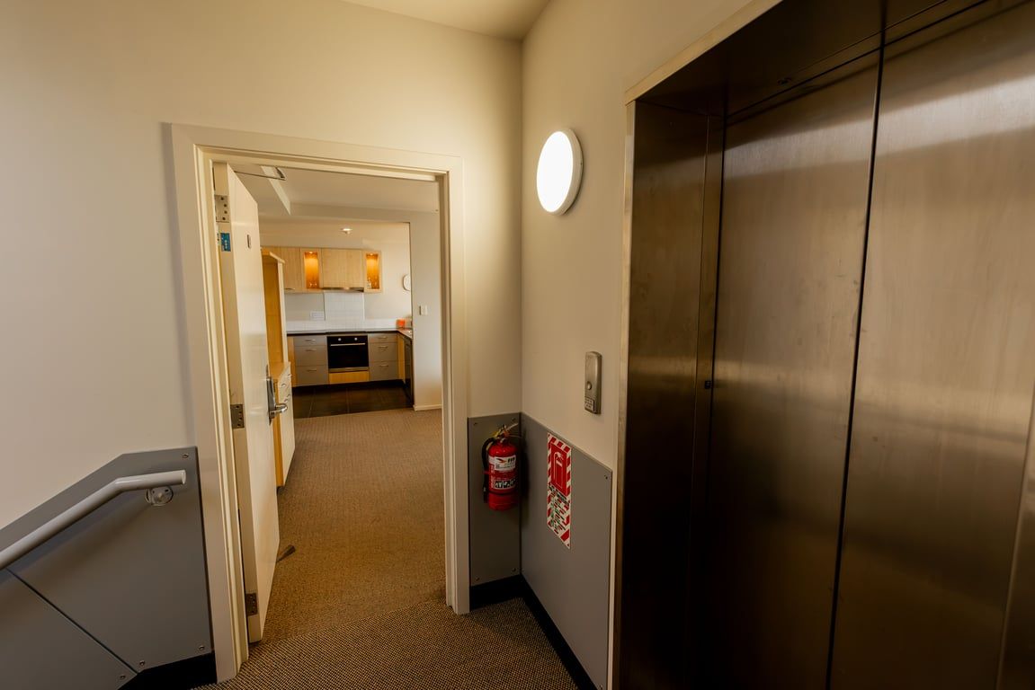 A hallway with a door leading to a kitchen area.