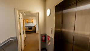 A hallway with a door leading to a kitchen area.