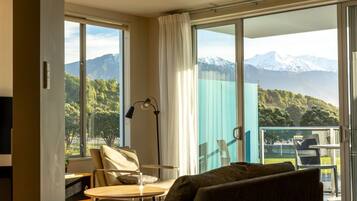 A modern room with a large sliding glass door leading to a balcony, a sofa, a table, and a lamp.
