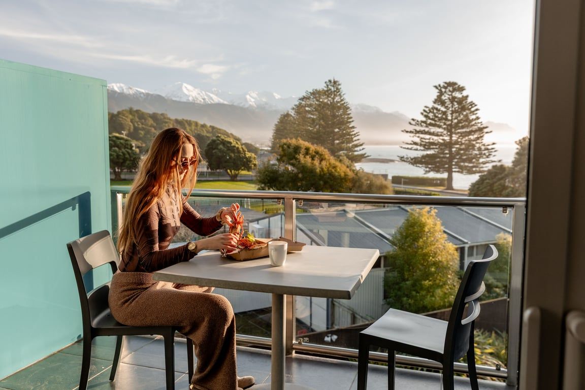 A person seated at a table with a view of mountains and trees.